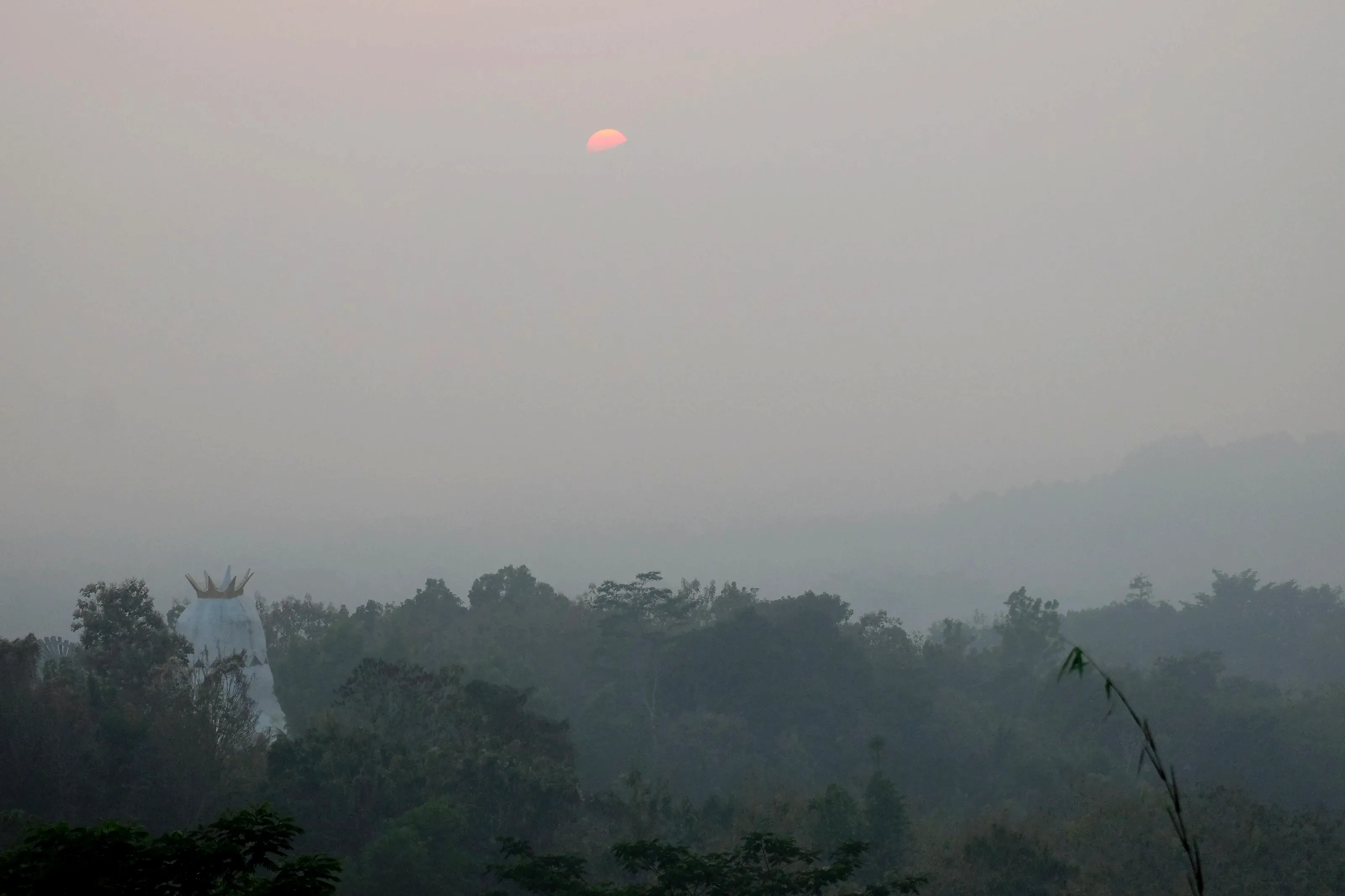 El sol saliendo sobre el valle desde Punthuk Setumbu, con la niebla sin levantar del todo.